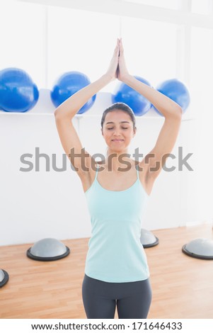 Beautiful young sporty woman with joined hands in fitness studio