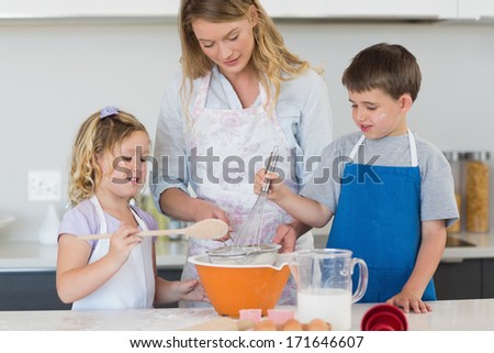Children and mother baking cookies at counter top in kitchen