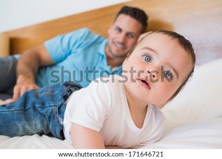 Cute baby boy with father in background on bed