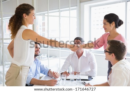 Businesswomen shaking hands at conference table in office