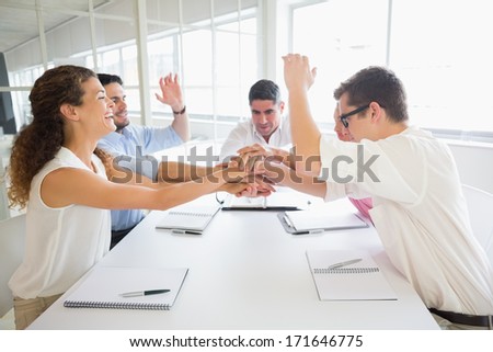 United business people stacking hands at conference table in office