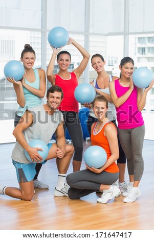 Portrait of happy fit young people with balls in a bright exercise room