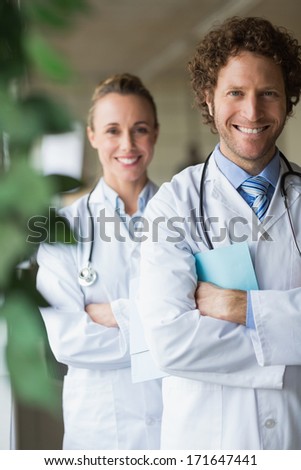 Portrait of happy doctors standing arms crossed in hospital