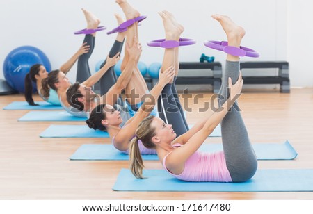 Side view of sporty young people with exercising rings in fitness studio