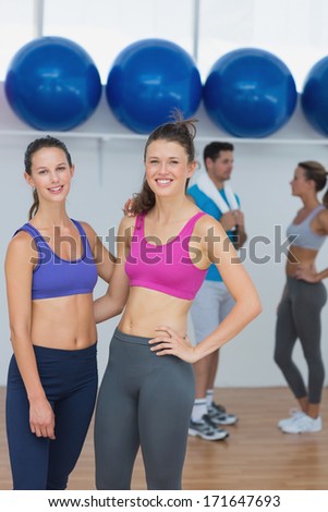 Portrait of fit young women in sports bra with a couple in background in fitness studio