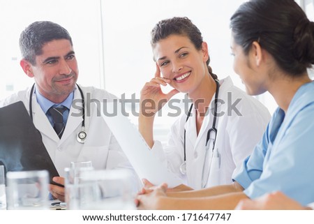 Smiling female doctor discussing with nurse and colleague in hospital