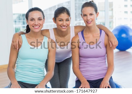 Portrait of three fit young women smiling in a bright exercise room