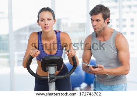 Male trainer watching woman work out at class in gym