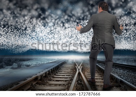 Businessman standing with arms out against train tracks under blanket of bright stars