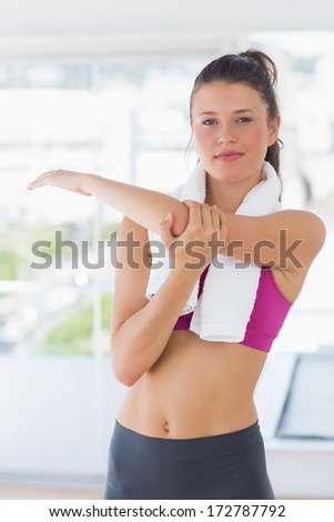 Portrait of a sporty young woman stretching hand at yoga class in fitness studio