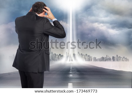 Stressed businessman with hands on head against open road
