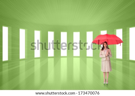 Attractive businesswoman holding red umbrella against bright green room with windows