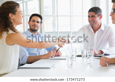 Business Partners Shaking Hands At Conference Table In Office