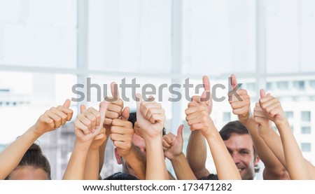 Closeup of cropped people gesturing thumbs up in a bright exercise room
