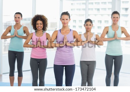 Portrait of a fit class standing with hands joined at a bright fitness studio
