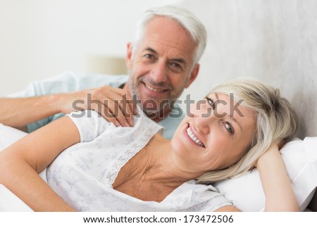 Closeup portrait of a smiling woman and mature man lying in bed at the home