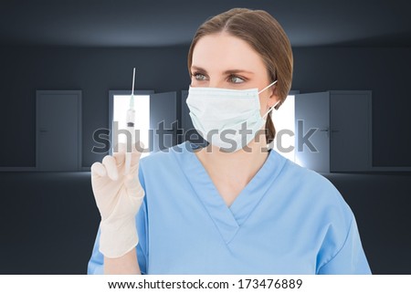 Pretty brunette female doctor holding a syringe and looking at it against doors opening revealing light