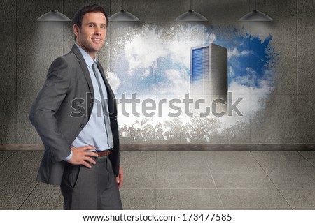 Smiling businessman with hand on hip against keyhole door in dark room