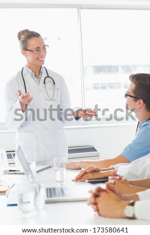 Happy female doctor discussing with colleagues in hospital