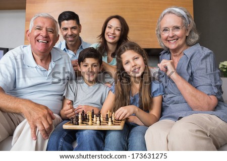 Portrait of happy extended family playing chess on sofa in the living room at home