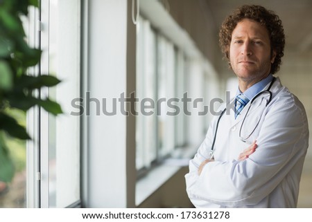 Portrait of confident male doctor standing arms crossed in hospital