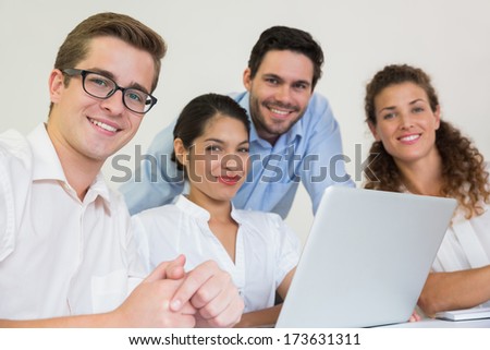 Portrait of confident business people with laptop at desk in office