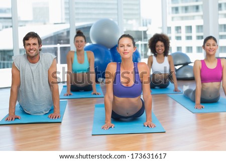 Portrait of a fit class doing the cobra pose in a bright fitness studioPortrait of a fit class doing the cobra pose in a bright fitness studio