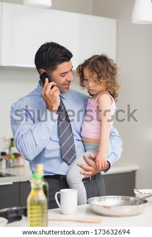 Well dressed father with daughter preparing food while on call in the kitchen at home