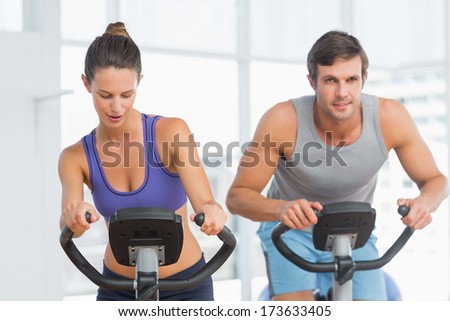 Smiling young man and woman working out at class in gym