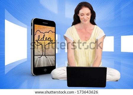 Happy woman using a laptop against bright blue room with windows