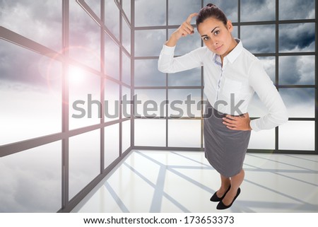 Focused businesswoman against gloomy sky seen through windows