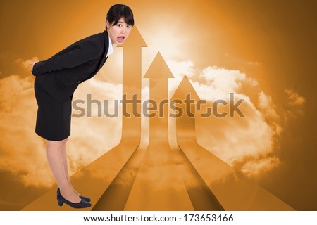 Surpised businesswoman bending against arrows in the sky in orange