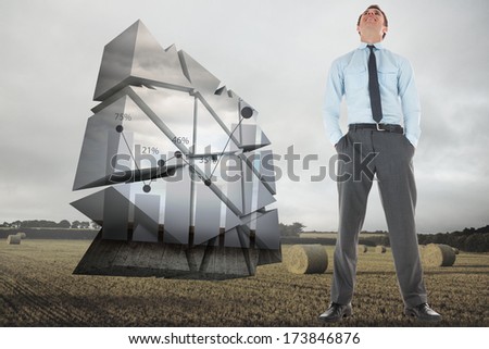 Happy businessman standing with hands in pockets against landscape with bales of straw