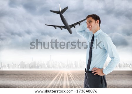 Thinking businessman with hand on head against city on the horizon