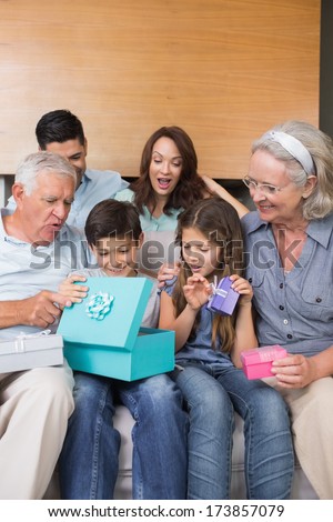 Cheerful extended family sitting on sofa with gift boxes in the living room at home