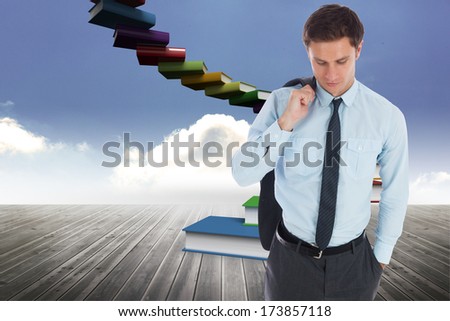 Serious businessman holding his jacket against book steps against sky