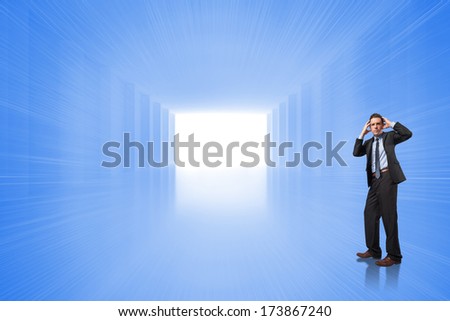 Stressed businessman with hands on head against bright blue room