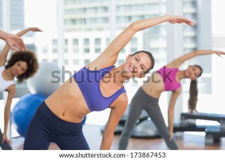 Portrait of sporty young women stretching hands at yoga class in fitness studio
