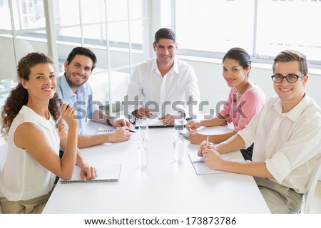 Portrait Of Smiling Business People Sitting At Conference Table In Office