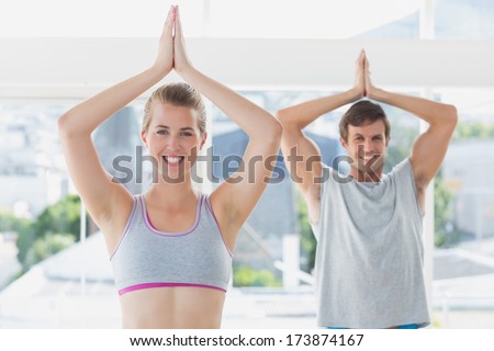 Portrait of a young sporty couple with joined hands in fitness studio