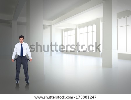 Sad tradesman showing his empty pockets against white room with windows