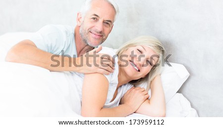 Portrait of a smiling woman and mature man lying in bed at the home