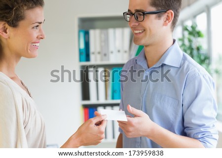 Smiling young business people exchanging visiting card in office