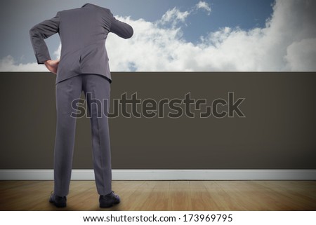 Thinking businessman scratching head against balcony and bright sky