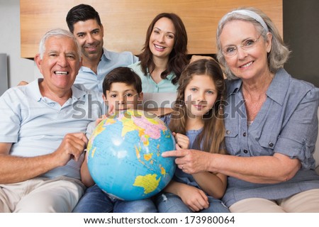 Portrait of an extended family sitting on sofa with globe in the living room at home