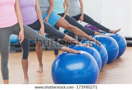 Low section of instructor and fitness class with exercise balls at fitness studio