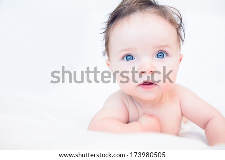 Portrait of lovely baby with blue eyes lying in bed