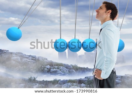 Thinking businessman with hand on head against newtons cradle above city in mountains