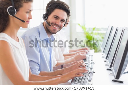 Portrait Of Customer Service Representative Working With Colleagues In Office