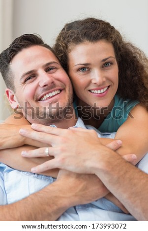 Portrait of smiling woman embracing man from behind at home